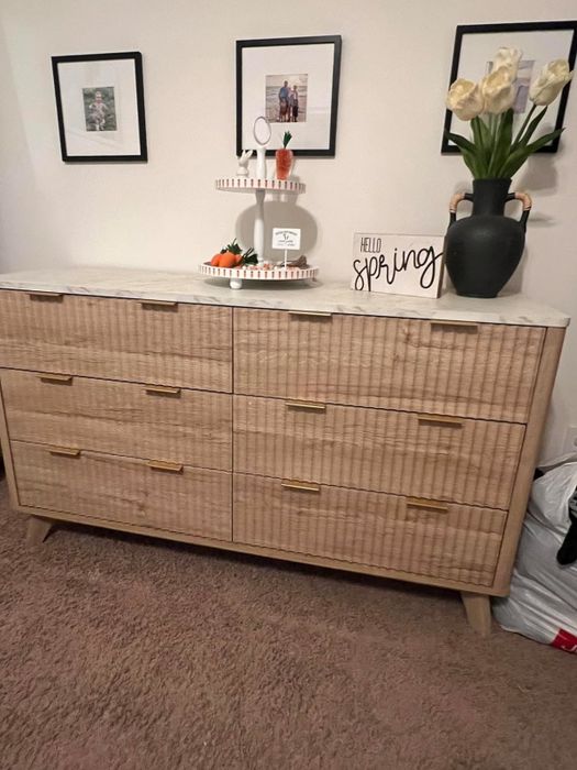 A dresser styled with a 'Hello Spring' sign, a vase of flowers, and a framed photo for a cheerful touch.