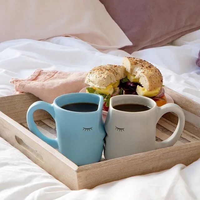 The mugs, placed together on a tray, sharing a kiss.
