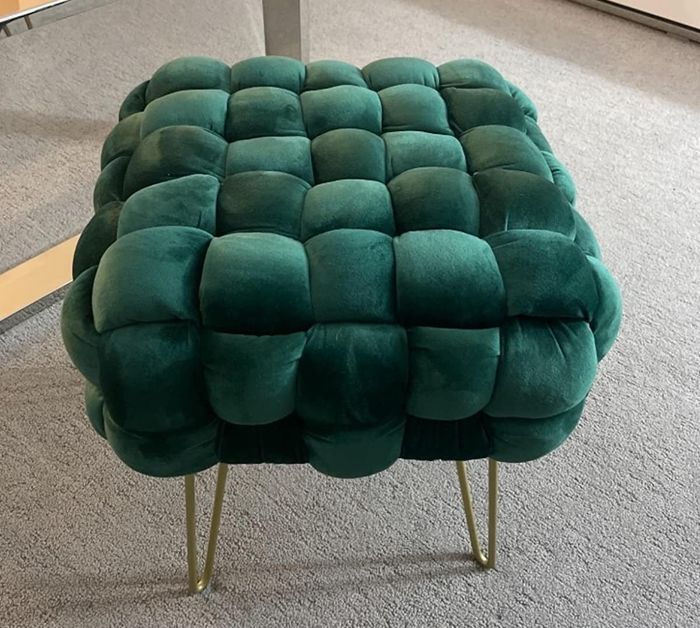 a reviewer photo showing the emerald green velvet ottoman with gold hairpin legs placed on a rug