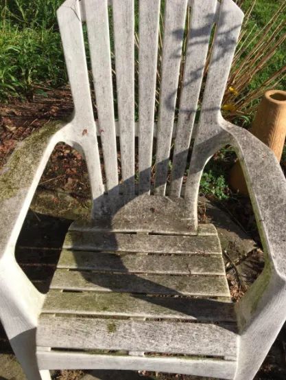 A reviewer's white patio chair covered in mold before applying the stain remover spray.