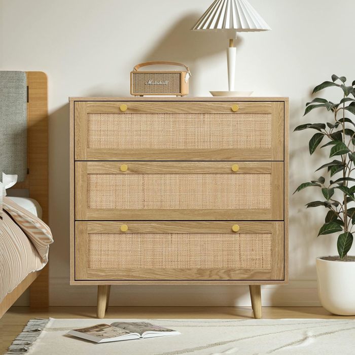 Wicker-front dresser with three drawers placed next to a bed, offering a practical bedroom storage solution.
