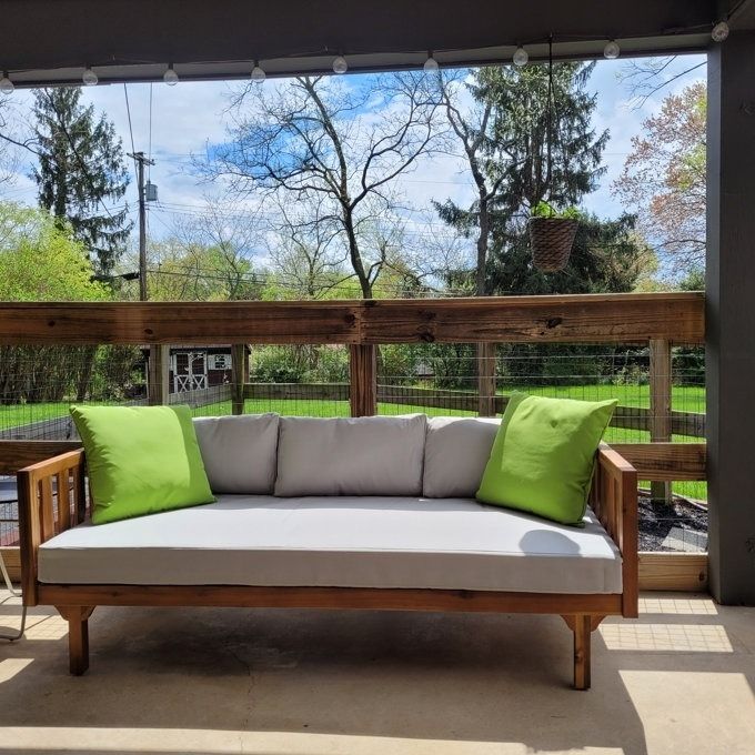 The daybed on a reviewer's porch, adorned with green pillows.
