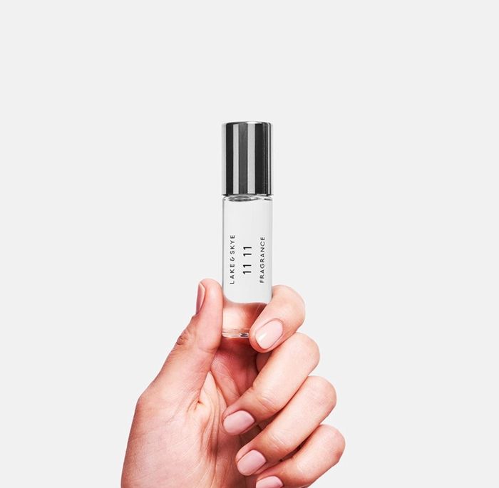 A model's hand holding the fragrance bottle