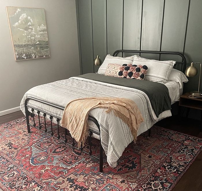 a reviewer photo showing the black frame bed in a bedroom with dark green walls