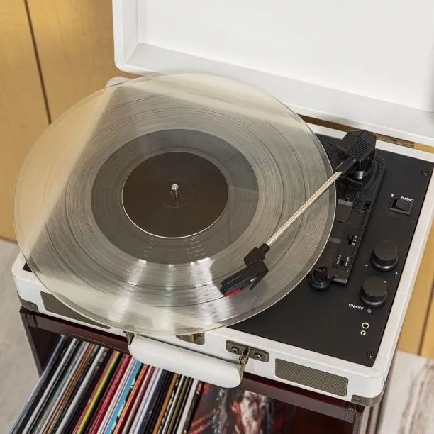 A white record player spinning a clear vinyl record.