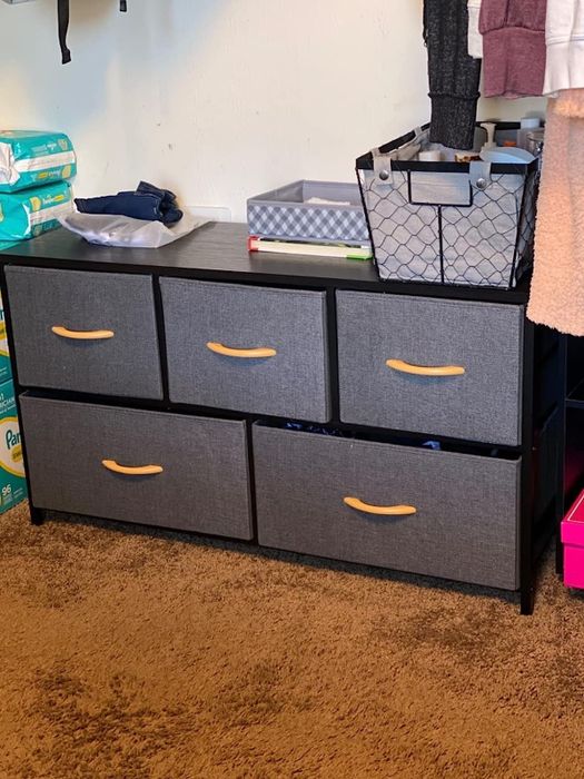 A gray dresser with various items stacked on top of it.