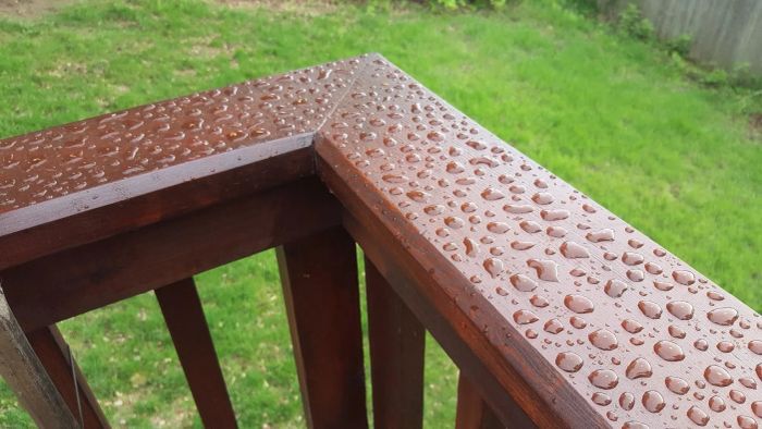 A photo from a reviewer showing the treated railing on their deck, illustrating how the treatment repels water droplets.