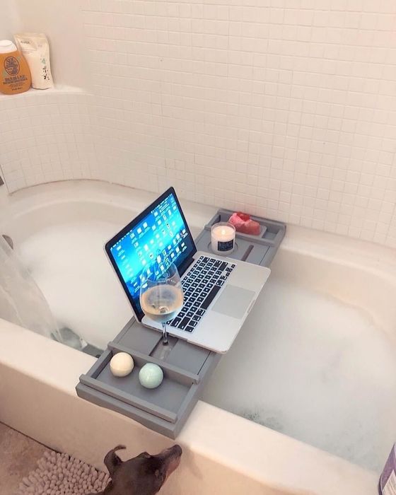 reviewer photo of a bath caddy with a laptop, wine, and a candle on it