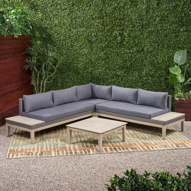 wooden sectional sofa featuring gray cushions and decorative pillows on a patio