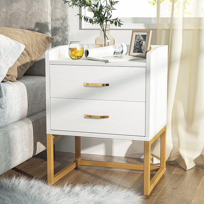the white and gold nightstand beside a bed