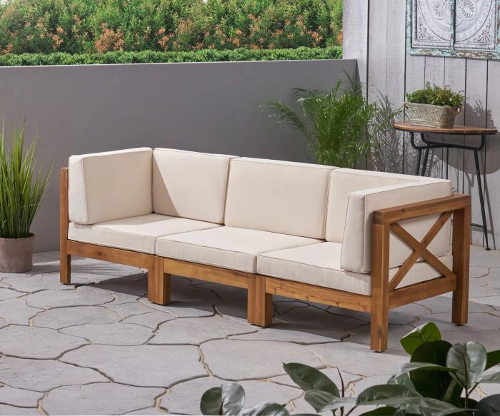 A wooden sofa with beige cushions is displayed on a patio setting.