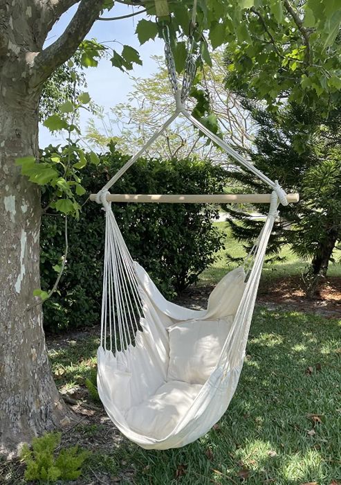 A photo from a reviewer showing the off-white hammock chair suspended from a tree.
