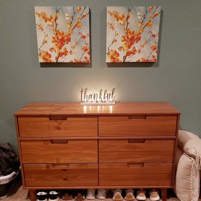 Reviewer showing the brown dresser with a glowing sign on top and shoes placed underneath