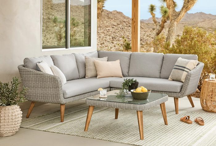 An outdoor furniture arrangement showcasing a gray sectional sofa, complemented by throw pillows and a coffee table