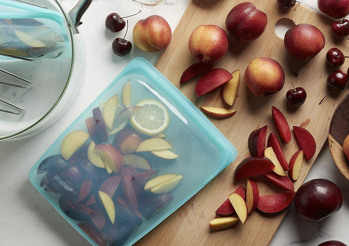 A see-through aqua Stasher bag packed with fresh fruit, ready for storage or snacking.