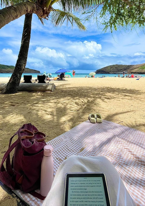 A reviewer enjoying the brown gingham picnic blanket