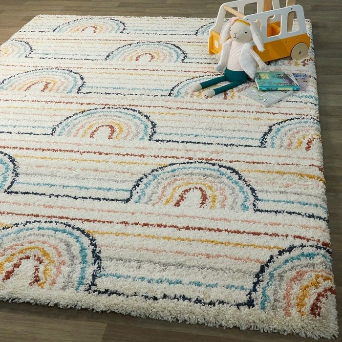 The rainbow-colored area rug adds a playful touch to a child’s room, sparking creativity.