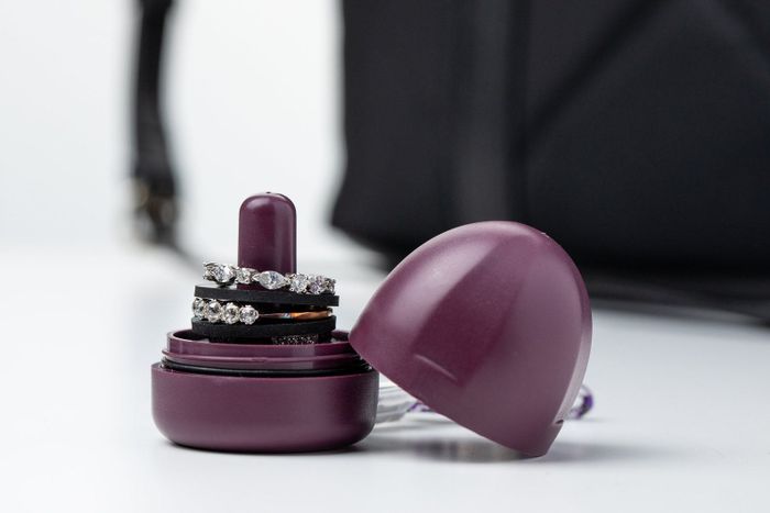 A compact purple dome-shaped storage unit with a cylindrical holder for several rings, topped with a twist-on lid.