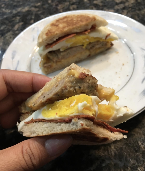 A reviewer holding a freshly made egg sandwich, showcasing the sandwich maker’s results.