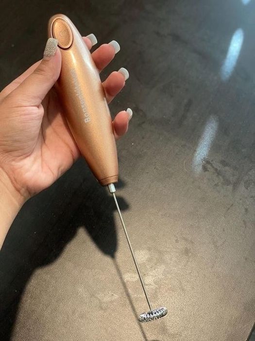 A reviewer holding the sleek, slender stick milk frother