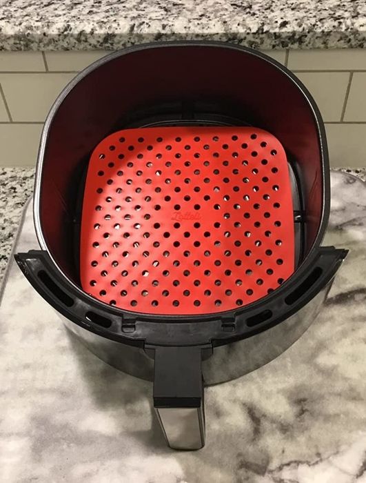A reviewer displaying the red silicone liner inside their air fryer.