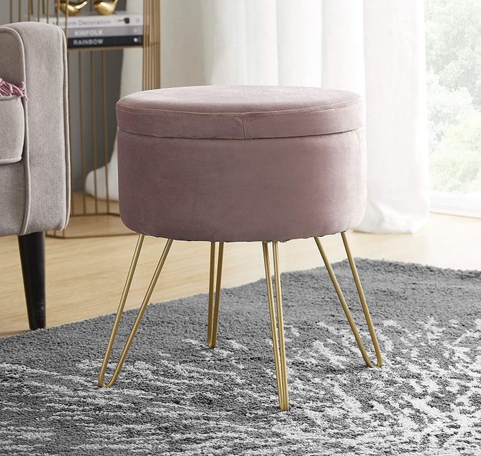A blush pink velvet ottoman with gold hairpin legs, featuring a removable lid.