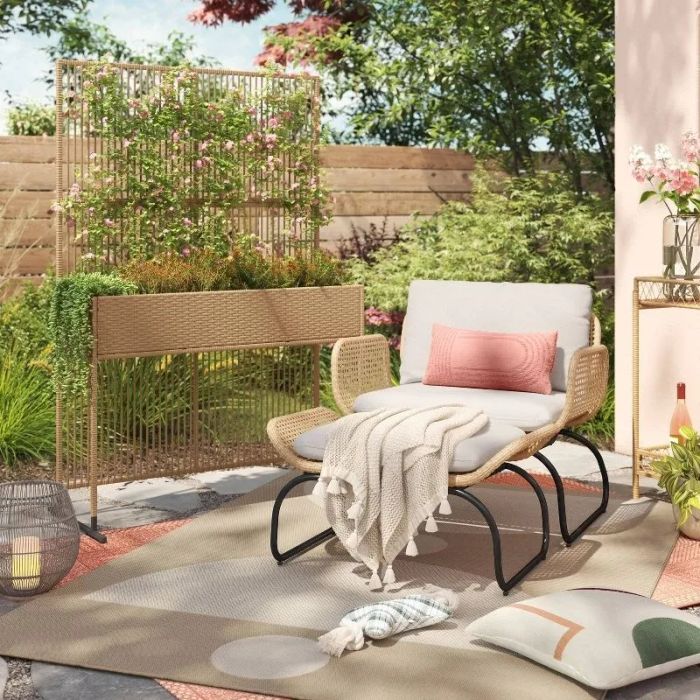 The privacy screen with plants placed on it next to a chair on a patio.