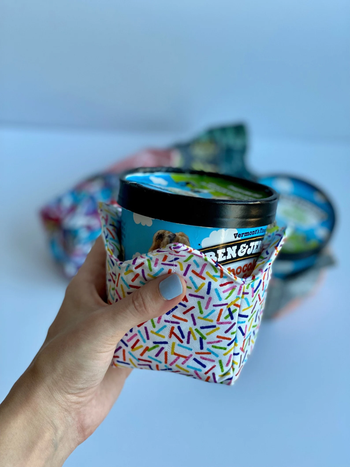A model holding a pint of ice cream wrapped in a sprinkle-patterned fabric cozy.