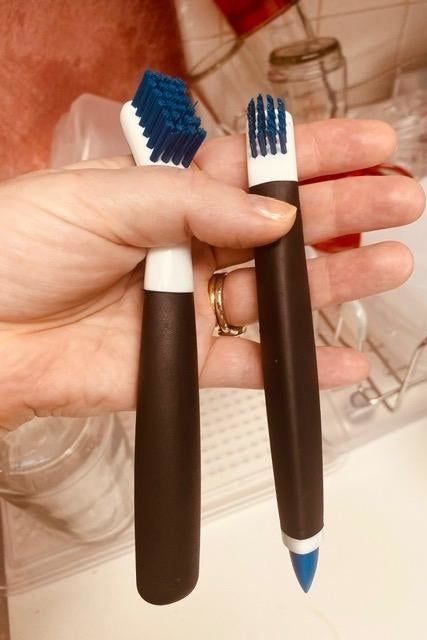 A reviewer's photo showing a hand holding two OXO cleaning brushes