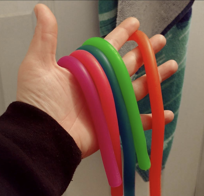 A review image showing five long, noodle-like toys in different colors.