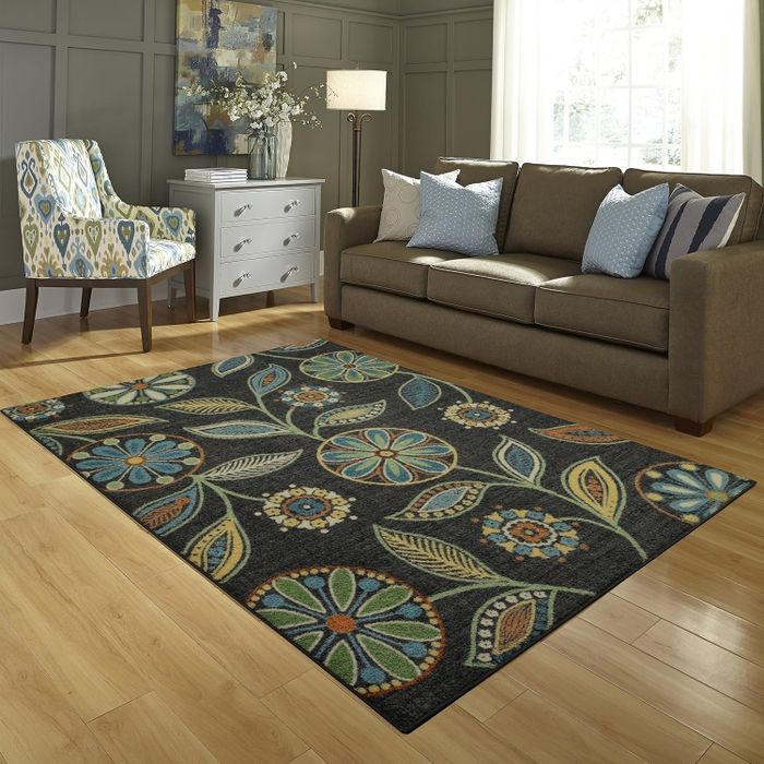 A black botanical patterned rug set against a beige background.