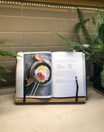 A reviewer using the holder to keep a recipe open in a cookbook.