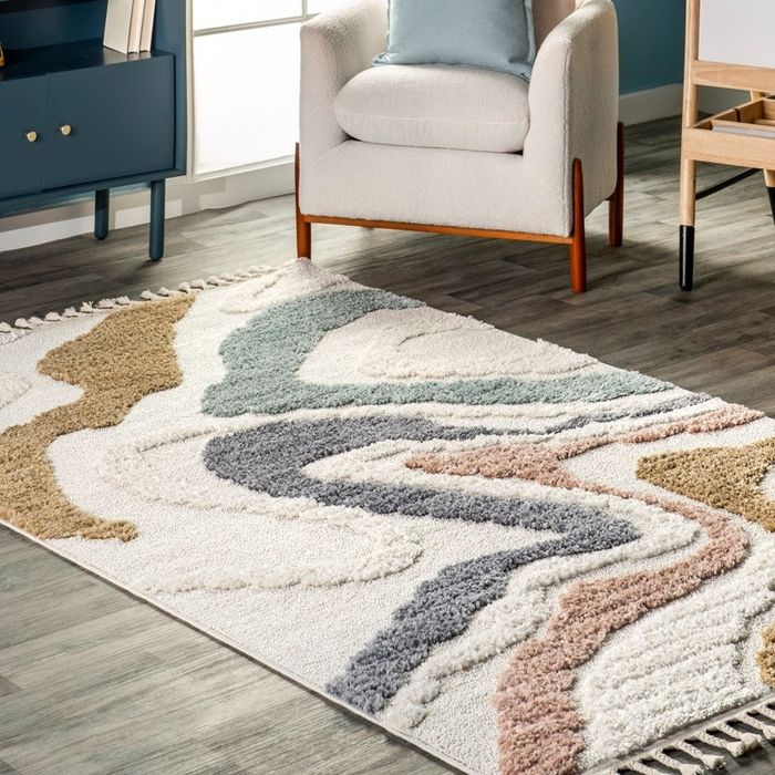 A modern living room with a cozy, textured area rug featuring wavy patterns, accompanied by a comfy armchair and wooden furniture.