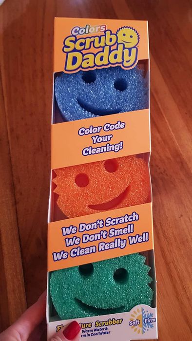 A reviewer holds up a three-pack of Scrub Daddy sponges.