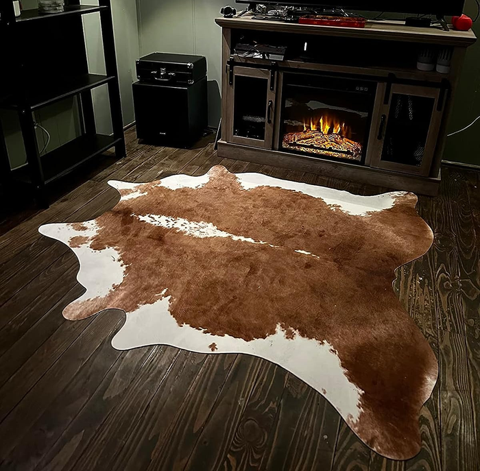 A reviewer’s image showcasing the brown cowhide rug in a cozy living room setting.