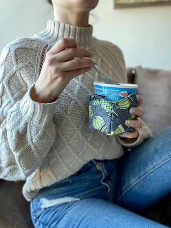Model holding a plant-patterned ice cream cozy.