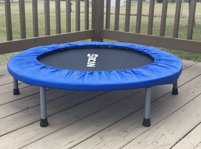 A reviewer’s snapshot of a compact trampoline featuring a blue safety cover around its edges.