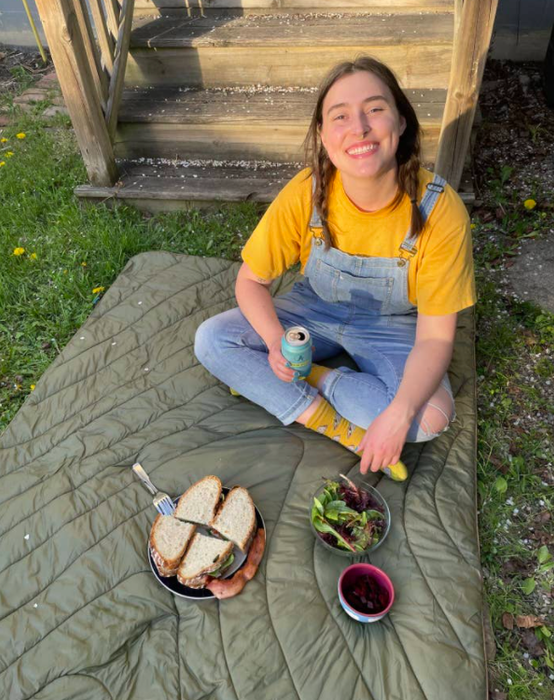 Mytour Reviews editor Rachel lounging on her cozy puffer blanket, with a delicious sandwich resting on a plate next to her. I'm just over here wondering why I wasn't invited to this picnic.