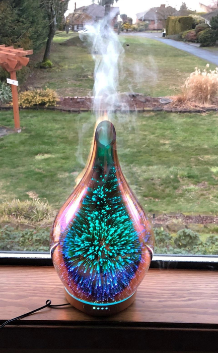 The same diffuser showing green and blue lights with a strong mist flowing out from the top