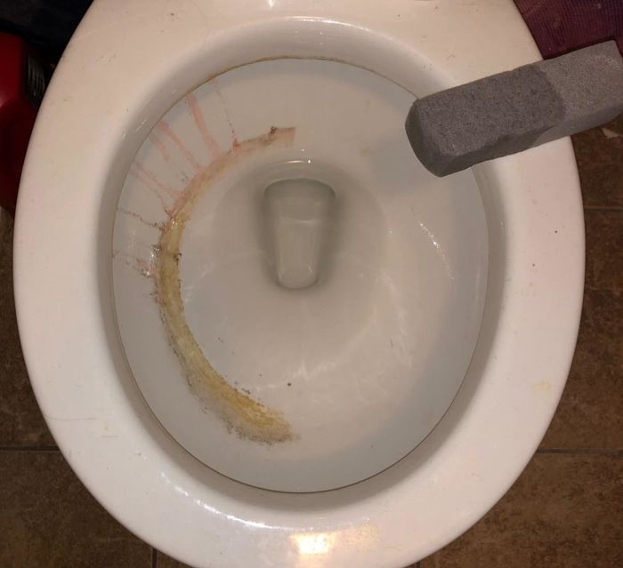 A reviewer’s photo showing their toilet partially cleaned with the pumice cleaning tool.