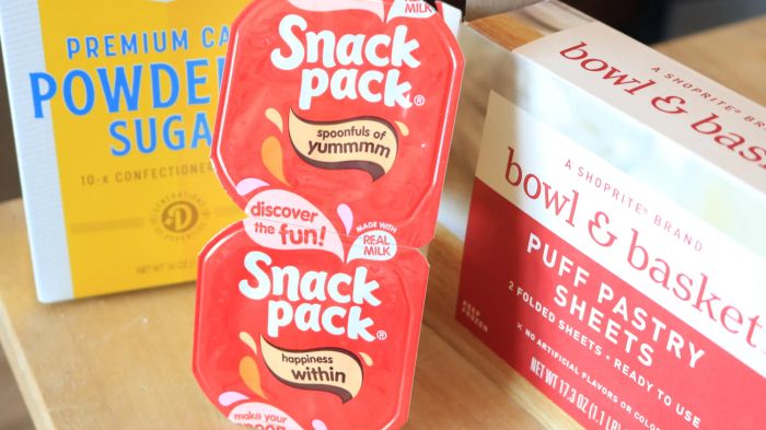 A table stacked with boxes of powdered sugar, puff pastry, and two containers of pudding.