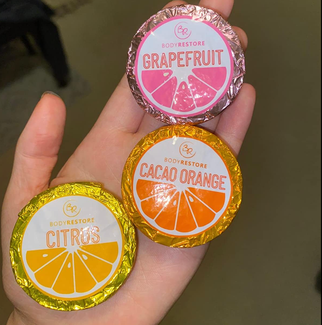 A reviewer holding three foil-wrapped shower steamers