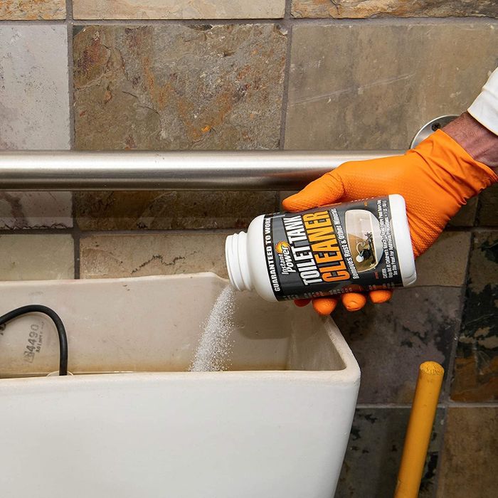 The toilet tank cleaning product being poured into the tank