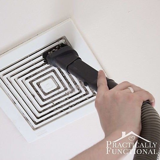 A blogger vacuuming the outside of an exhaust fan.