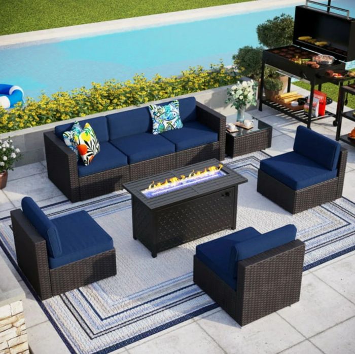 A dark wicker and navy-cushioned patio set centered around a fire pit table, combining style and comfort for your outdoor gatherings.