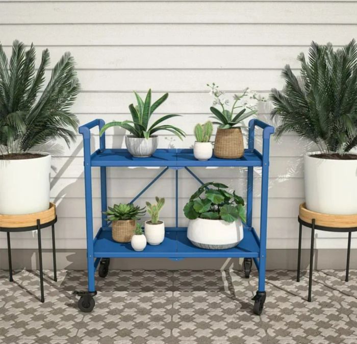 A blue steel cart filled with vibrant plants, placed in a beautifully decorated outdoor area.