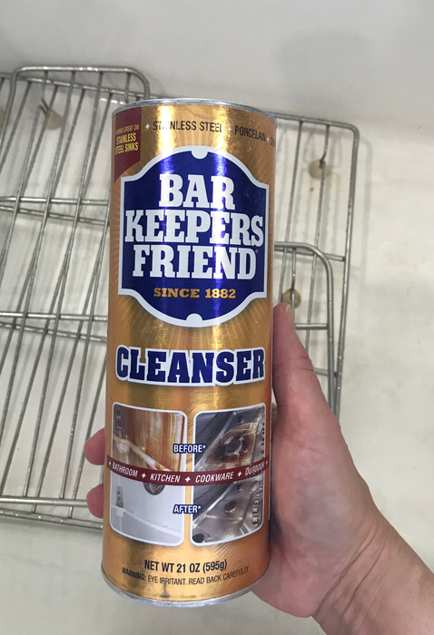 A reviewer holding a bottle of powdered cleanser over the sink