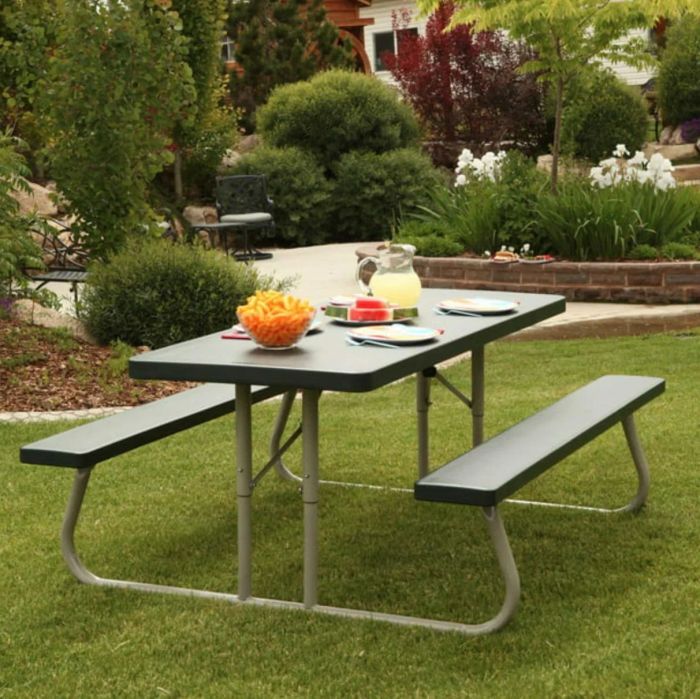 A green picnic table with a sturdy metal frame, set up in a well-decorated outdoor area, perfect for family meals or outdoor fun.