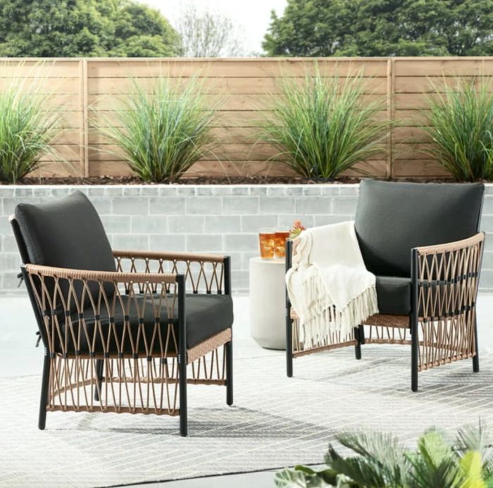 Wicker-sided armchairs with black cushions, beautifully arranged in a decorated patio space.