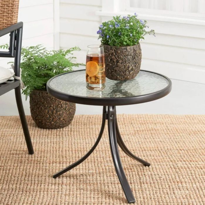 A sleek metal and glass side table positioned in a beautifully designed patio space, perfect for your essentials.